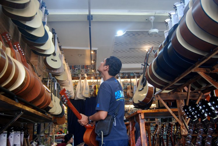 Pengunjung toko gitar di Medan melihat gitar yang hendak dibeli