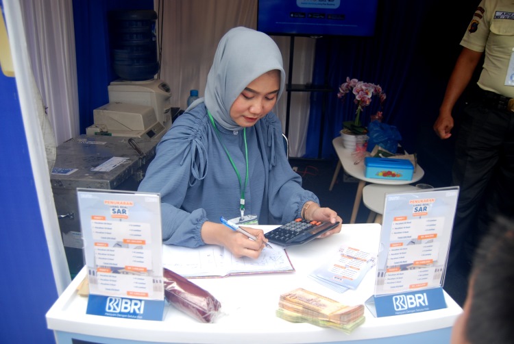 Petugas penukaran uang Riyal di gerai penukaran uang milik BRI di Asrama Haji Medan sedang menghitung uang
