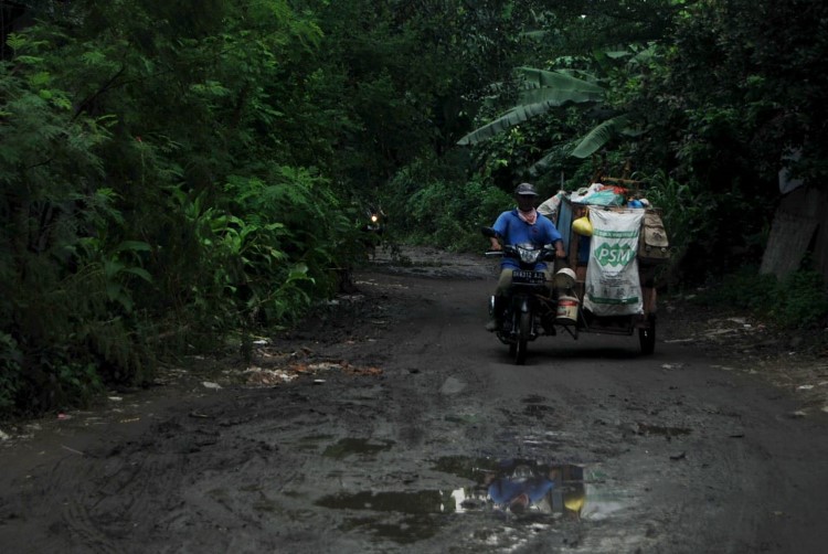 Petugas sampah mengendarai becak roda tiga sambil mengangkut sampah di Medan