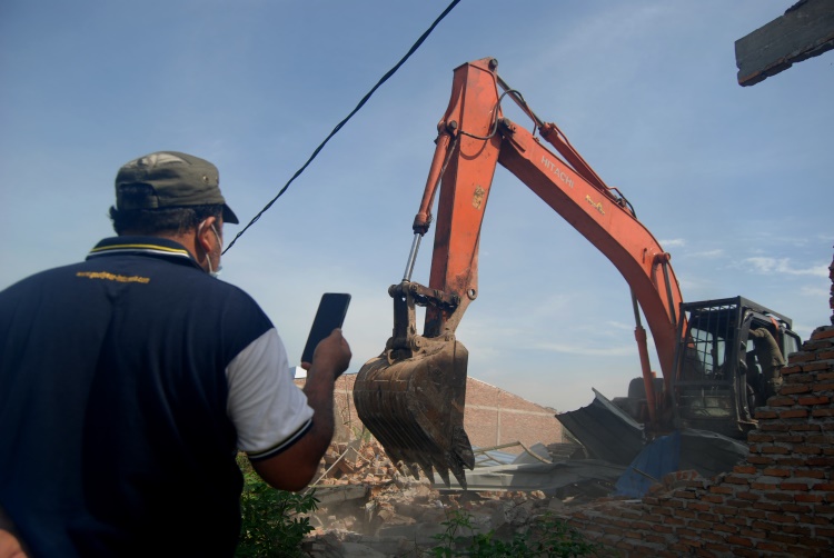 Satu unit Ekskavator merubuhkan bangunan di Desa Sampali