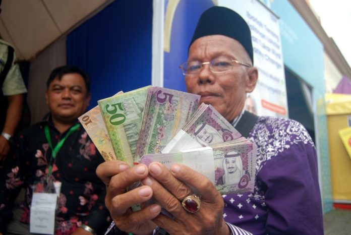 Seorang Jamaah calon haji di Asrama Haji Medan menunjukan sejumlah pecahan uang Riyal