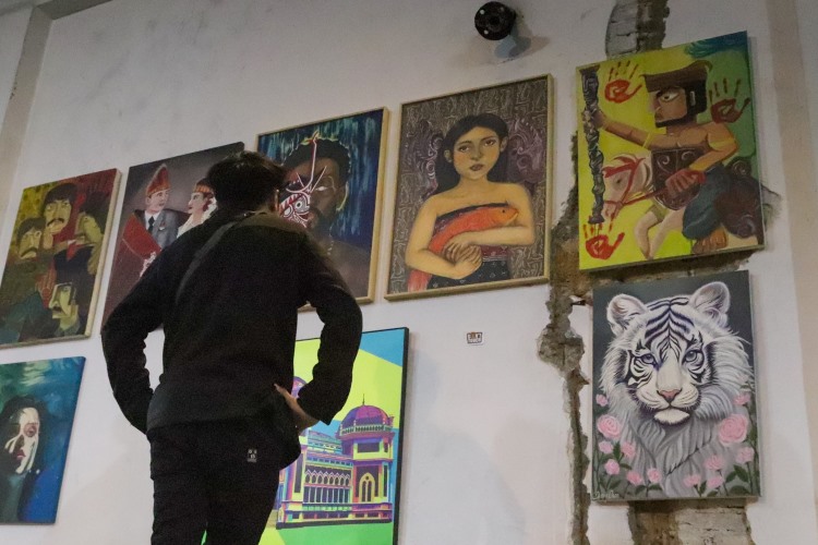 Seorang pengunjung memerhatikan sebuah lukisan yang dipajang di Urban Culture Exhibition dan Angsa Neduh