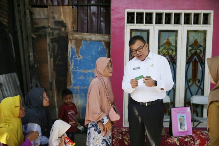 Kadinkes Deli Serdang, dr. Asri Ludin Tambunan membagikan KIS gratis dari pemerintah untuk warga kurang mampu di Kecamatan Batang Kuis (f:rinaldi samosir/mistar)