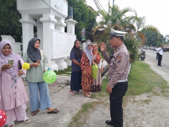 Personel Lantas Polres Tanjung Balai saat memberikan edukasi bagi pengguna jalan yang melintas di depan Polres Tanjung Balai (f:saufi/mistar)