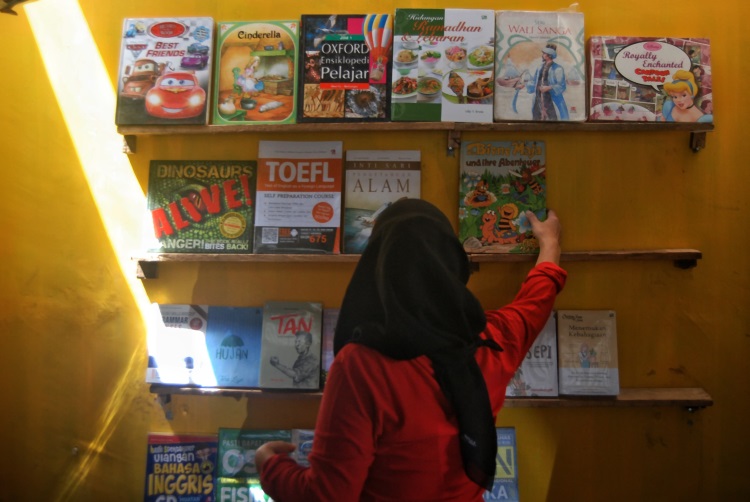 Pedagang buku bekas di titi gantung Medan merapikan dagangan di atas rak dinding