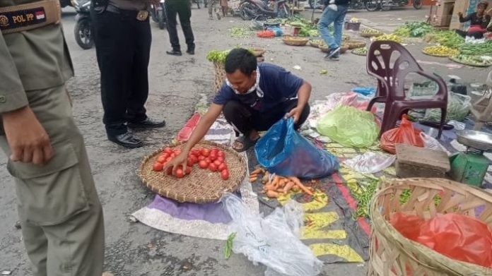 Pedagang sayuran mengemas dagangannya setelah mendapat imbauan dari petugas gabungan