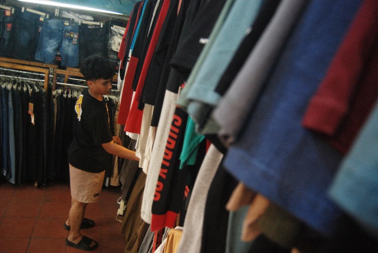 Pekerja salah satu toko pakaian di Medan, Sumatera Utara menyusun barang ke atas rak