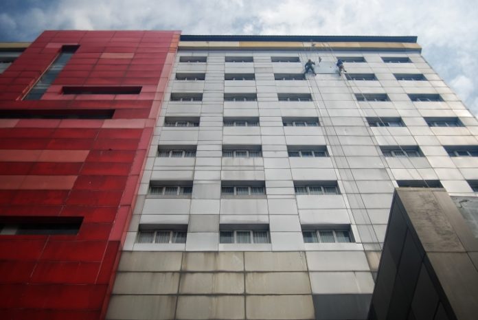 Pekerja tengah memperbaiki dinding luar gedung salah satu hotel di Kota Medan