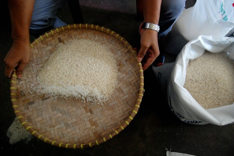 Pemilik toko di Medan sedang menampi beras