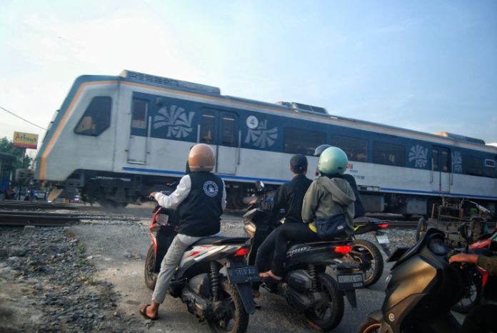 Pengendara roda dua mengantri di jalur kereta api tanpa palang pintu di Jalan Padang, Kota Medan