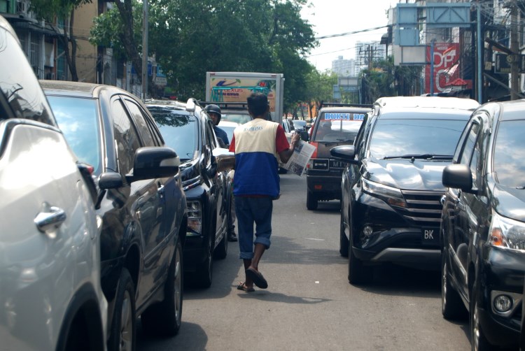 Penjual koran menjajakan dagangannya kepada pengguna jalan di persimpangan lampu merah Jalan Brigjend Katamso, Medan