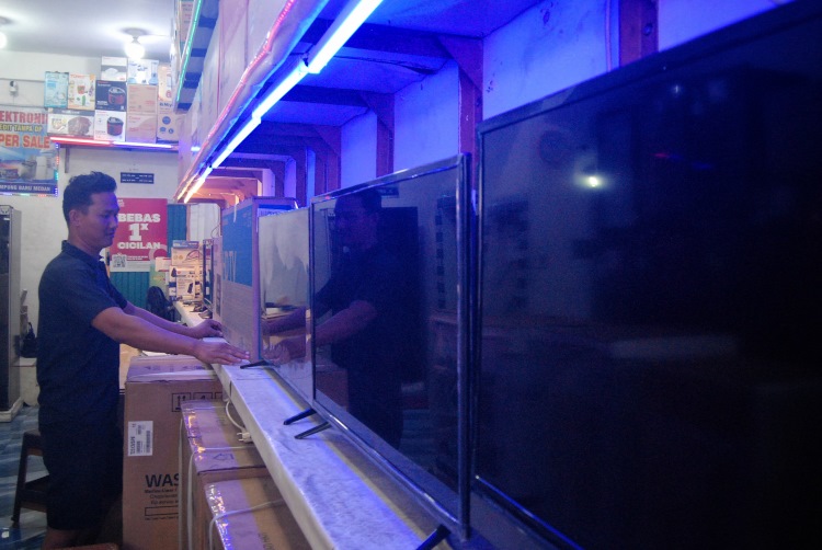 Salah seorang pekerja toko elektronik di Medan merapikan susunan TV