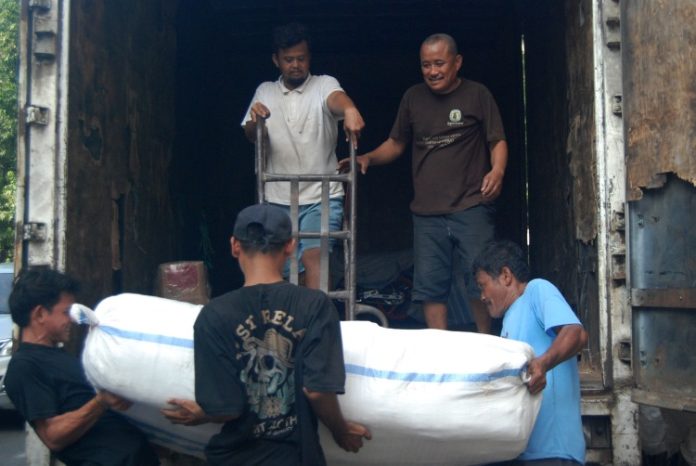 Sejumlah pekerja informal di Medan dengan susah payah mengangkat barang ke dalam mobil angkutan untuk dikirim