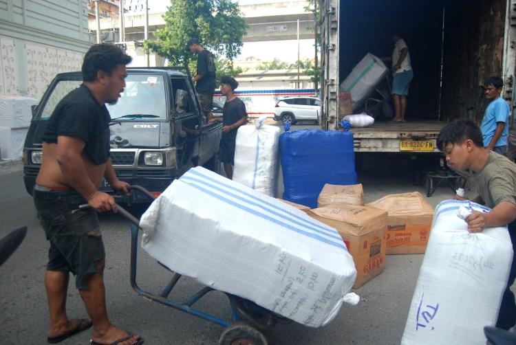 Sejumlah pekerja informal di Medan menyusun barang yang akan dikirim