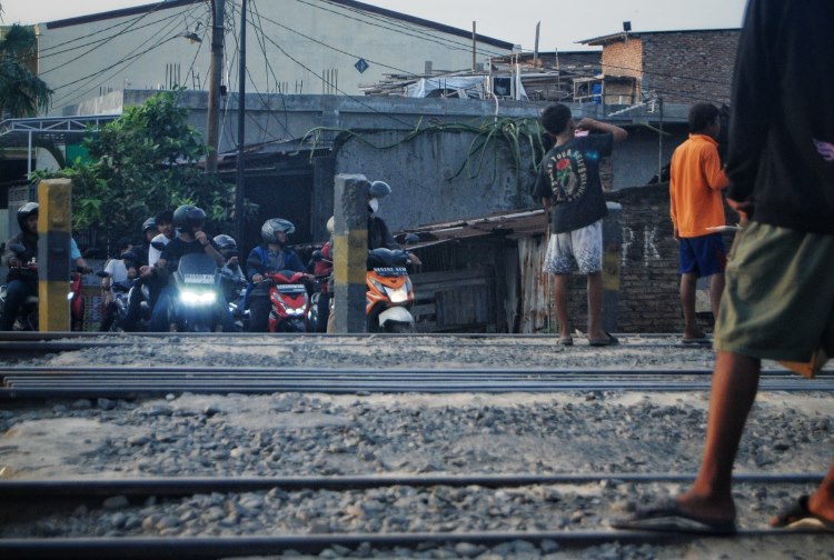 Sejumlah warga mengatur pengendara roda dua saat melintas di jalur kereta api tanpa palang pintu di Jalan Padang Kota Medan