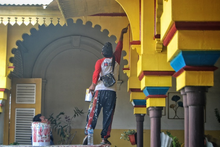 Seorang pekerja melakukan pengecatan dinding luar Istana Maimun Medan