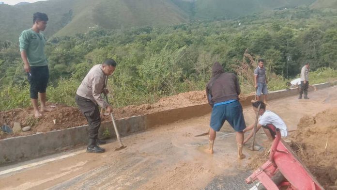 Personel Polsek Harian membersihkan tanh longsor bersama masyarakat.(f:ist/mistar)