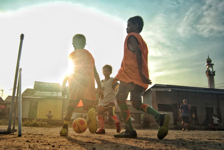 Anak-anak bermain sepak bola di Lahan Gedung Serbaguna Gudang Arang, Medan Belawan