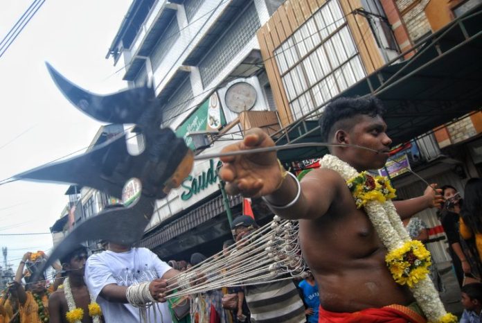 Besi panjang menembus pipi seorang pria yang mengikuti ritual Thaipusam pada perayaan Adhi Mahapuja Thiruvila di Medan