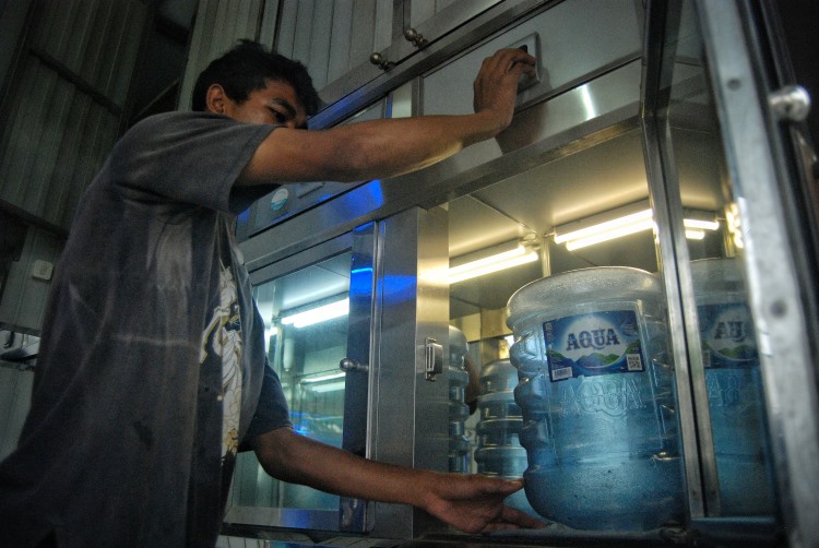 Pekerja depot air minum di Medan melakukan penyemprotan galon kosong