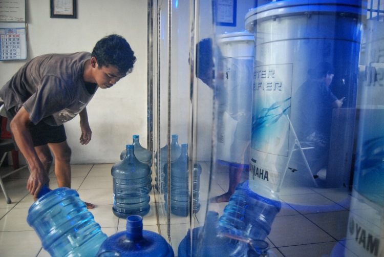 Pekerja depot air minum isi ulang di Medan menyusun sejumlah galon berisi air