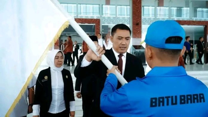 Pj Bupati Batu Bara Heri Wahyudi Marpaung menyerahkan pataka kontingen Popprovsu Kabupaten Batu Bara. (f : ist/mistar)