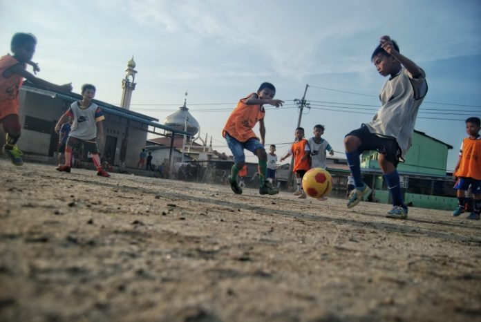 Sejumlah anak bermain sepak bola dengan semangat di Lahan Gedung Serbaguna Gudang Arang, Medan Belawan