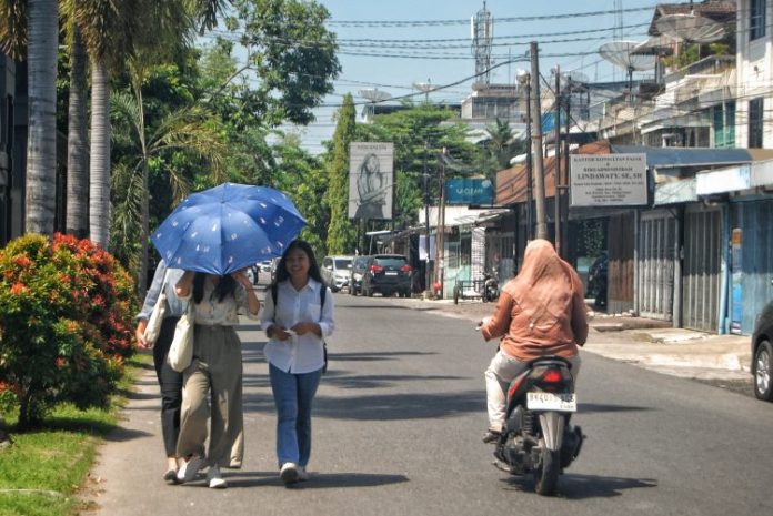 Sejumlah warga menggunakan payung saat berada di luar ruangan di Kota Medan akibat cuaca panas