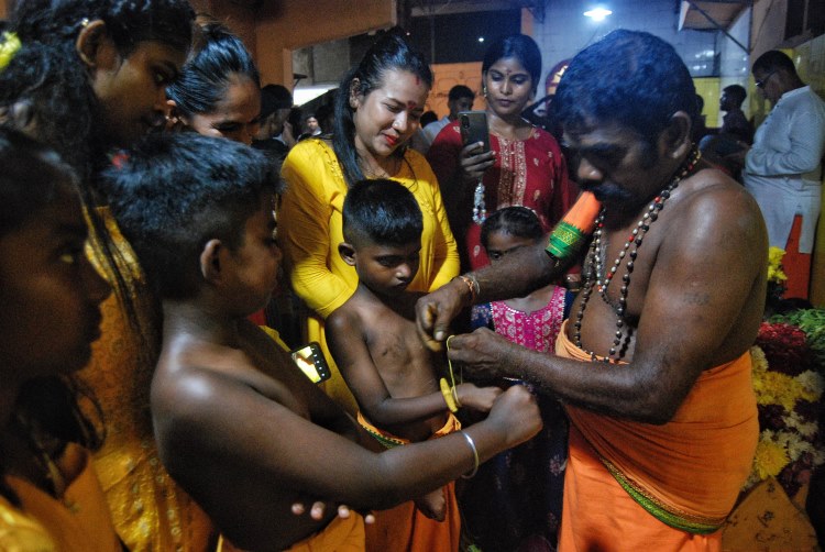Seorang Pandita mengikat gelang kepada seorang anak etnis Tamil di Medan