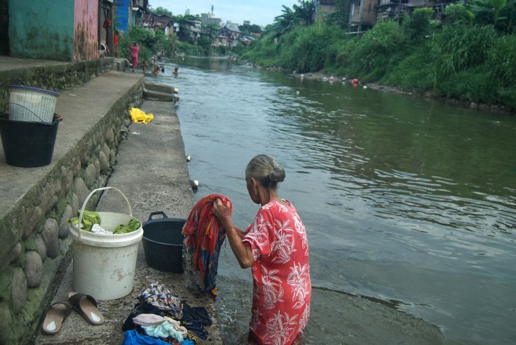 Seorang ibu terlihat mencuci pakaian di Sungai Deli, Kampung Aur, Medan
