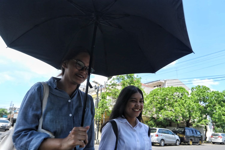 Warga Kota Medan memilih menggunakan payung agar terhindar dari cuaca panas