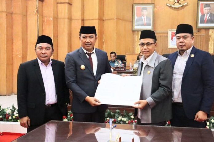 Pj Bupati Heri Wahyudi Marpaung bersama Ketua DPRD Safi'i didampingi 2 Wakil Ketua DPRD menunjukkan berita acara pengesahan Ranperda menjadi Perda. (f : ist/mistar)