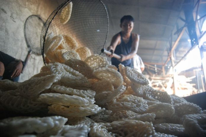 Pekerja menuang kerupuk mawar usai di goreng di industri rumahan UMKM di Desa Bandar Khalipah, Percut Sei Tuan, Deli Serdang, Sumatera Utara