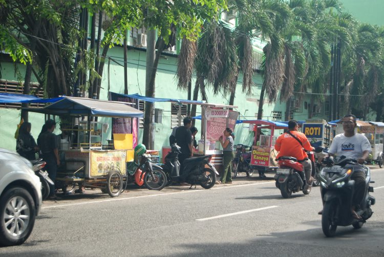 Pengendara melintas dengan latar belakang gerai pelaku Usaha Mikro Kecil Menengah (UMKM) di Jalan Turi, Medan, Sumatera Utara