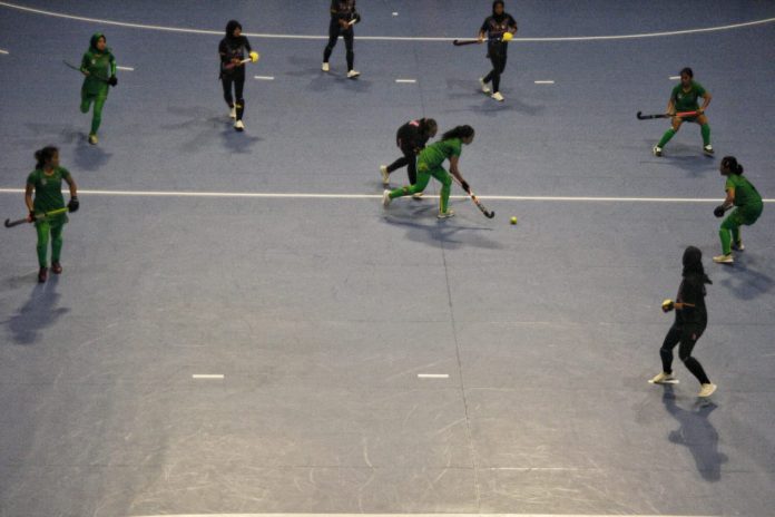 Atlet hoki indoor putri Sumatera Utara (hijau) menggiring bola di tengah para pemain tim hoki putri Lampung pada pertandingan penyisihan PON XXI Aceh Sumut