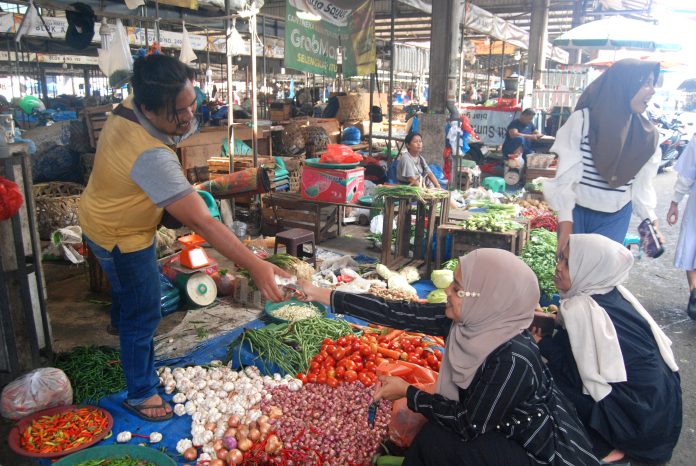 Pedagang melakukan transaksi saat melayani pembeli di Pasar Aksara, Medan