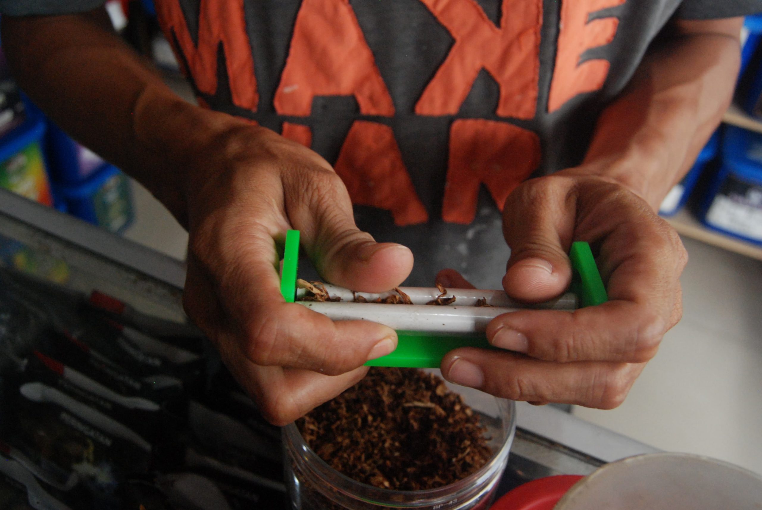 Seorang warga sedang melinting tembakau yang baru saja dibeli di Toko Tembakau Makmur, Deli Tua, Deli Serdang