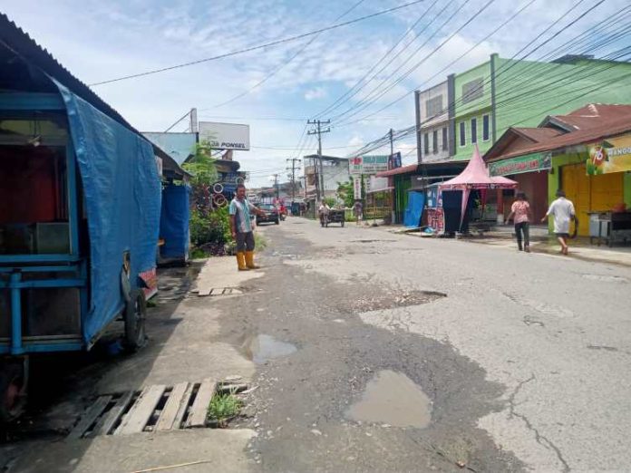 Salah seorang warga menunjuk satu lubang di Jalan Sei Mencirim, Dusun III, Desa Payageli. (f:putra/mistar)