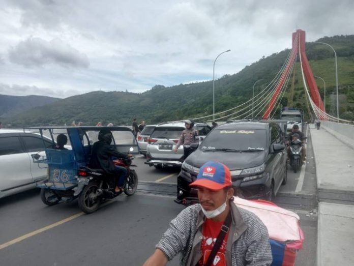 Petugas Patwal Polresta Samosir menghalau pelancong untuk tidak memarkirkan mobilnya di Jembatan Tano Ponggol Samosir.