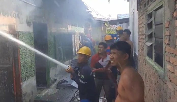 Petugas memadamkan api di rumah kontrakan yang terbakar di Kisaran