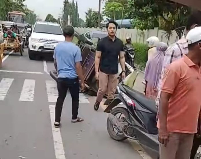 Kondisi becak mesin milik Wak Becak terbalik usai diseruduk mobil di Jalan Arteri Bandara Kualanamu