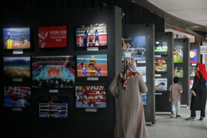 Sejumlah pengunjung mengamati karya foto yang dipamerkan pada pameran foto PON XXI Aceh-Sumut di Deli Park Mall Medan