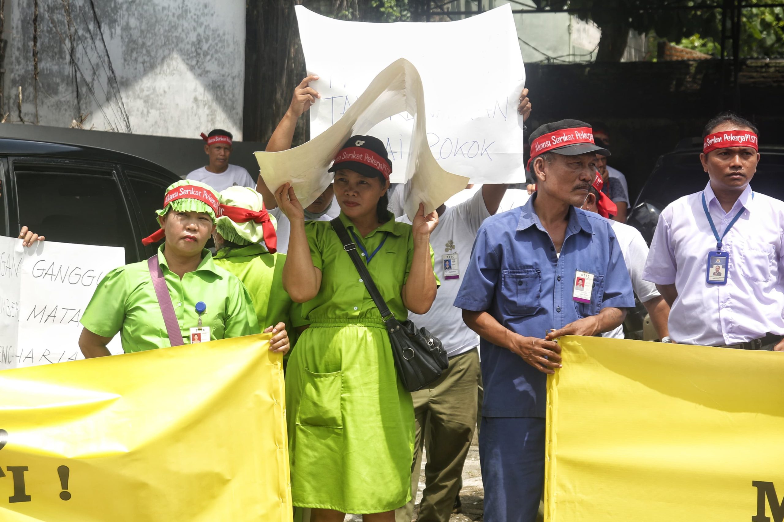 Seorang buruh dari PT STTC berteduh dari terik matahari saat berunjuk rasa kantor dinas ketenagakerjaan Pematangsiantar