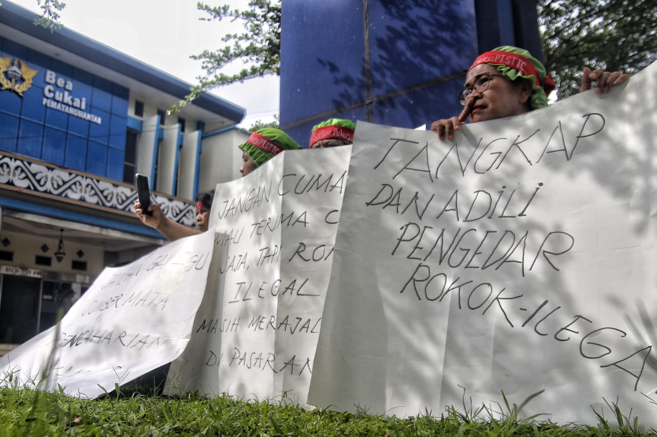 Seorang buruh duduk sambil memegang spanduk tuntutan di depan halaman Kantor Pengawasan dan Pelayanan Bea Cukai (KPPBC) Pematangsiantar