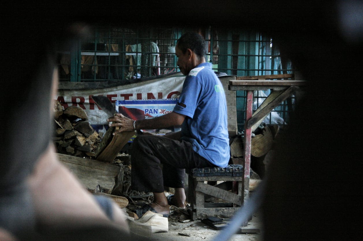 Seorang perajin cetakan sepatu sedang membelah kayu di Medan Denai, Medan, Sumatera Utara