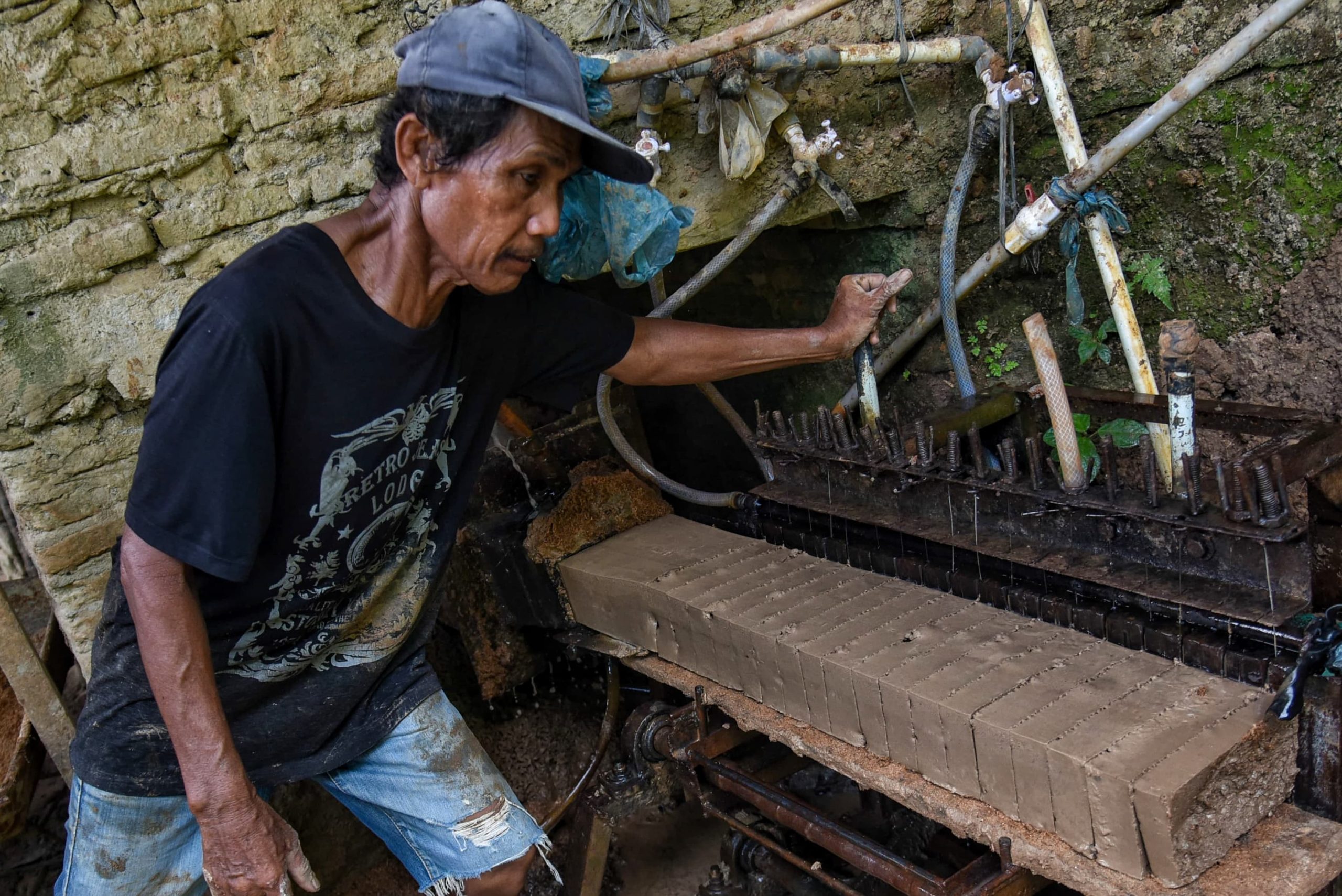 Seorang perajin memotong batu bata yang baru dicetak di Pakam, Deli Serdang, Sumatera Utara