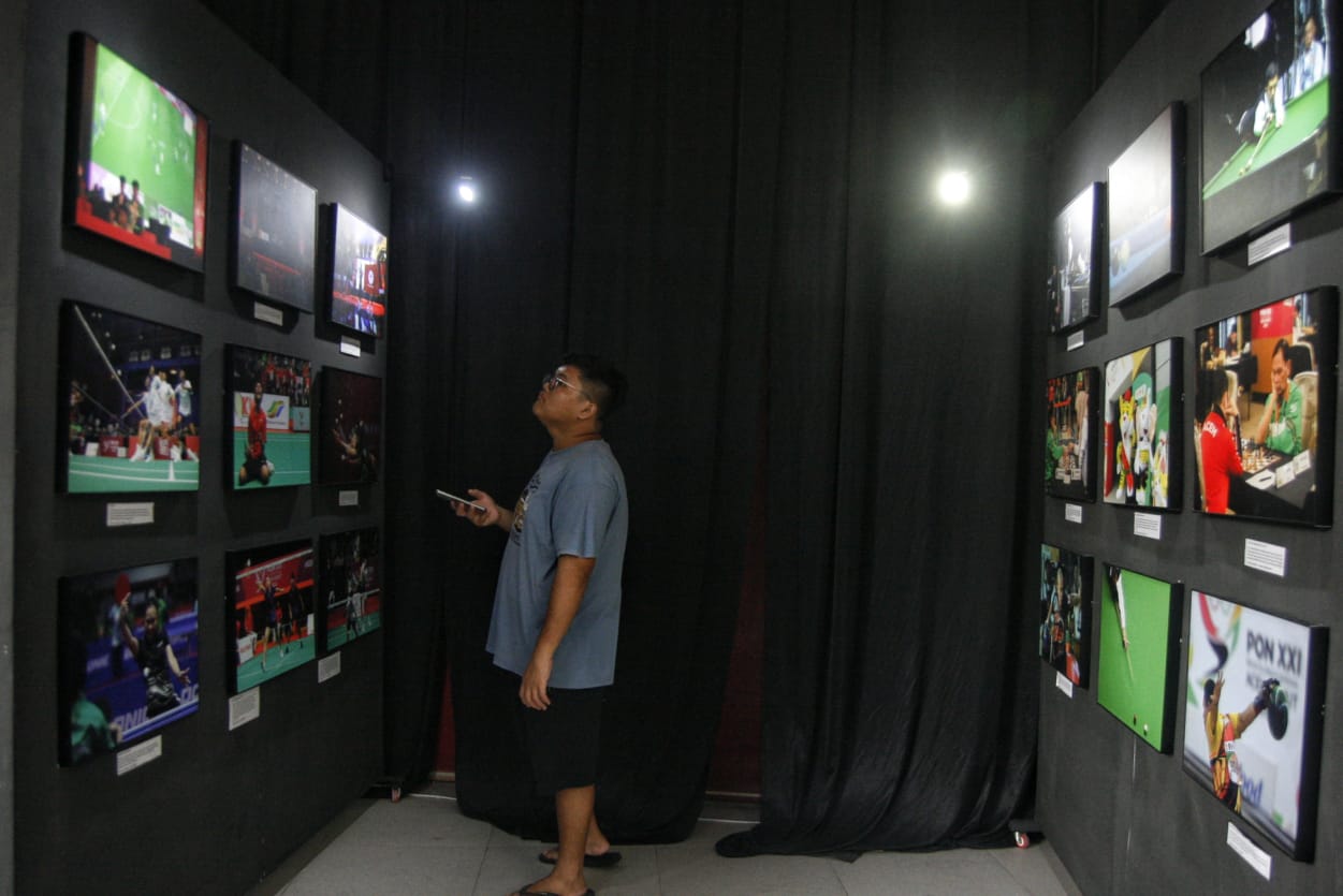 Seorang warga mengamati sebuah foto dengan sangat serius dalam pameran foto PON XXI Aceh Sumut di Deli Park Mall Medan, Sumatera Utara