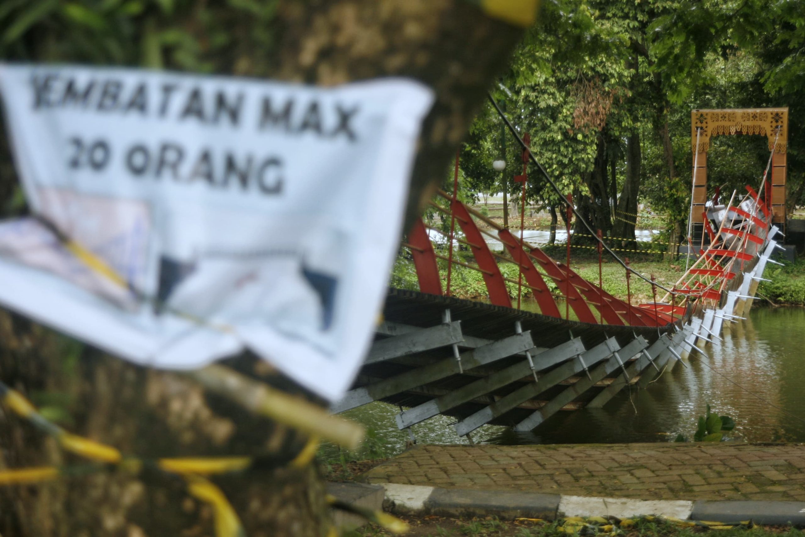 Spanduk kecil bertuliskan jumlah maksimal orang yang boleh melewati jembatan yang ambruk di Taman Cadika, Medan, Sumatera Utara