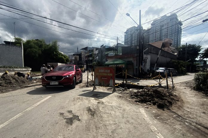 Warga melintasi proyek pembangunan saluran pembuangan air (drainase) di Jalan Taruma, Medan