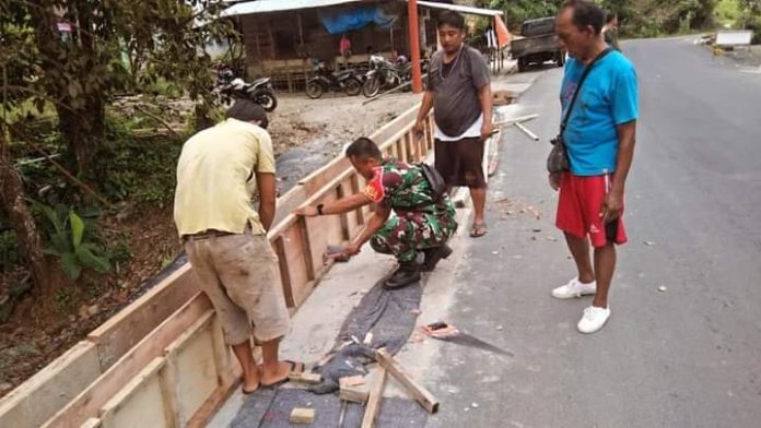 Babinsa Koramil 05/Kolang Koptu Febri bergotongroyong bersama warga Desa Bonan Dolok membangun pembatas jalan.